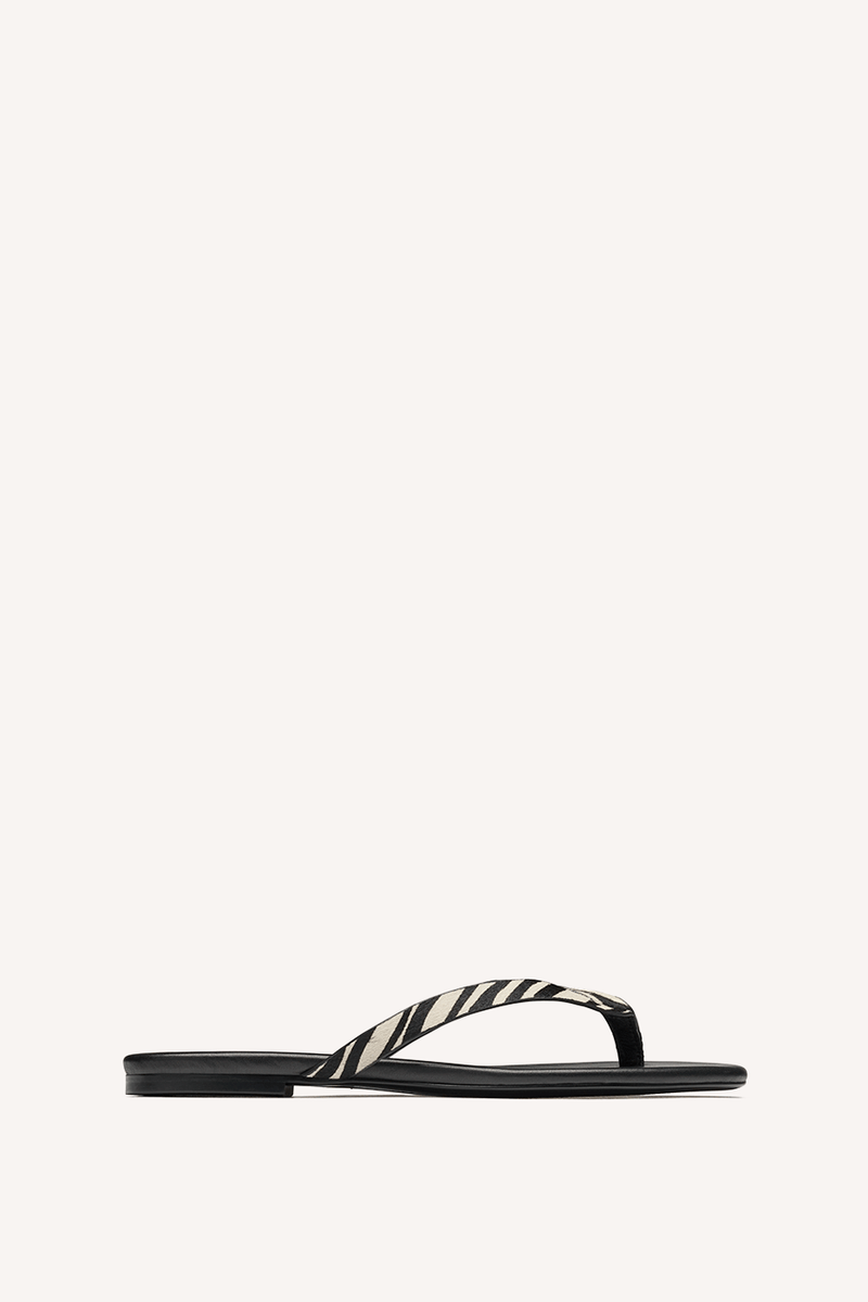 Nelson Made zebra print thong sandal with a flat black sole and thin straps, shown in profile against a solid off-white background.